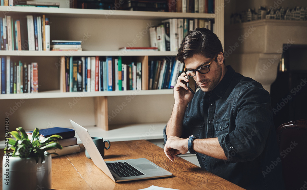 Time isnt on my side today. Shot of a handsome young businessman making a phone call while working 