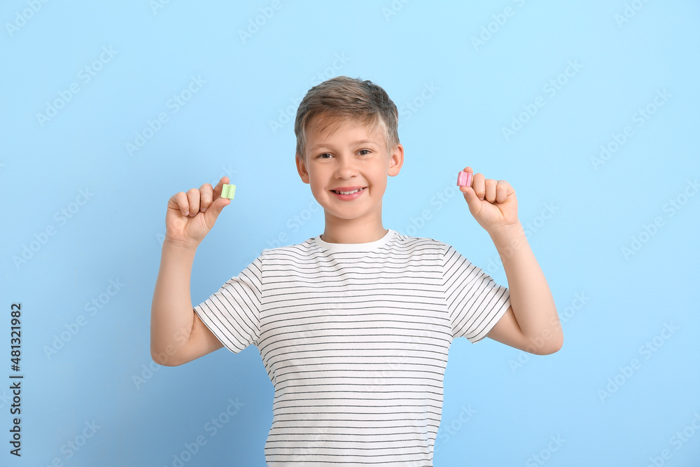 Little boy with chewing gums on blue background