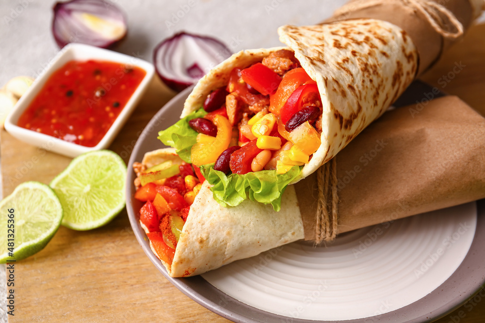 Board with delicious burritos and sauce on table, closeup