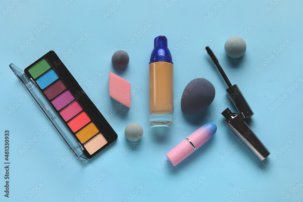 Makeup sponges and cosmetic products on blue background