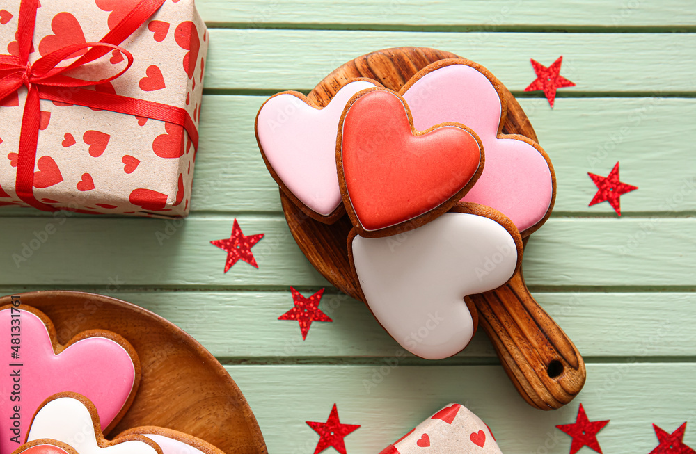 Board with tasty heart shaped cookies on green wooden background