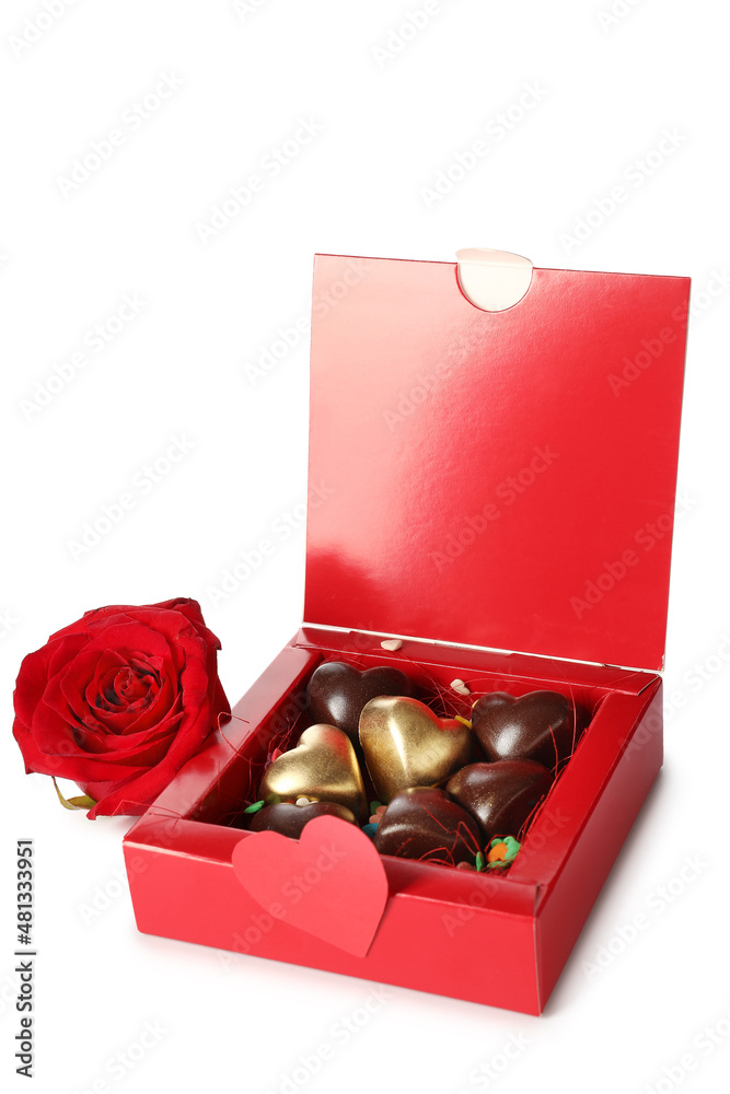 Box with tasty heart-shaped candies and rose on white background