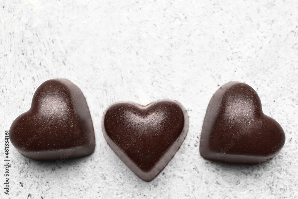 Tasty heart-shaped candies on light background