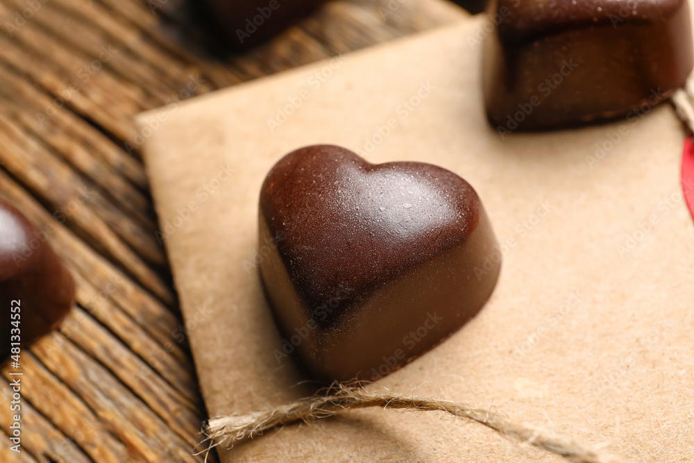 Tasty heart-shaped candy on wooden background, closeup