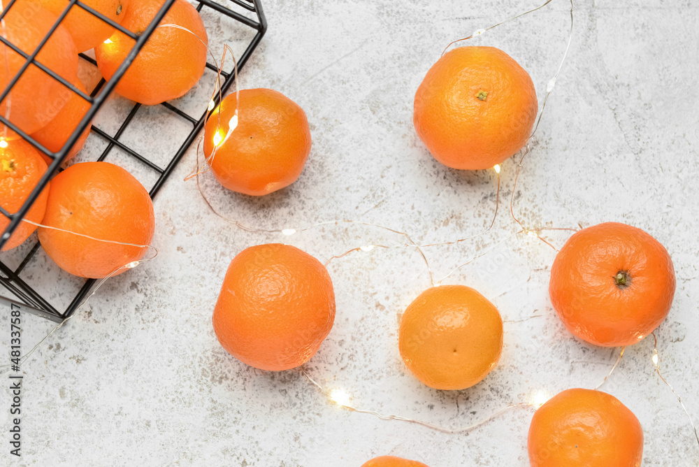 Basket with tasty tangerines on light background