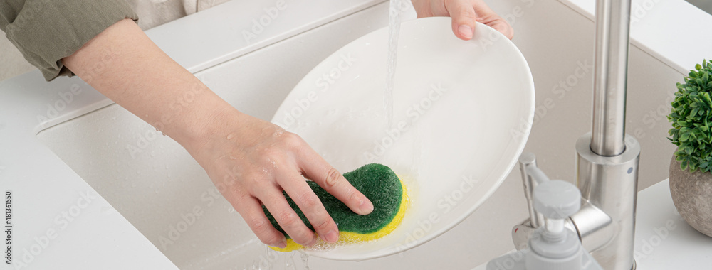 Woman housewife is doing the dishes at home kitchen.