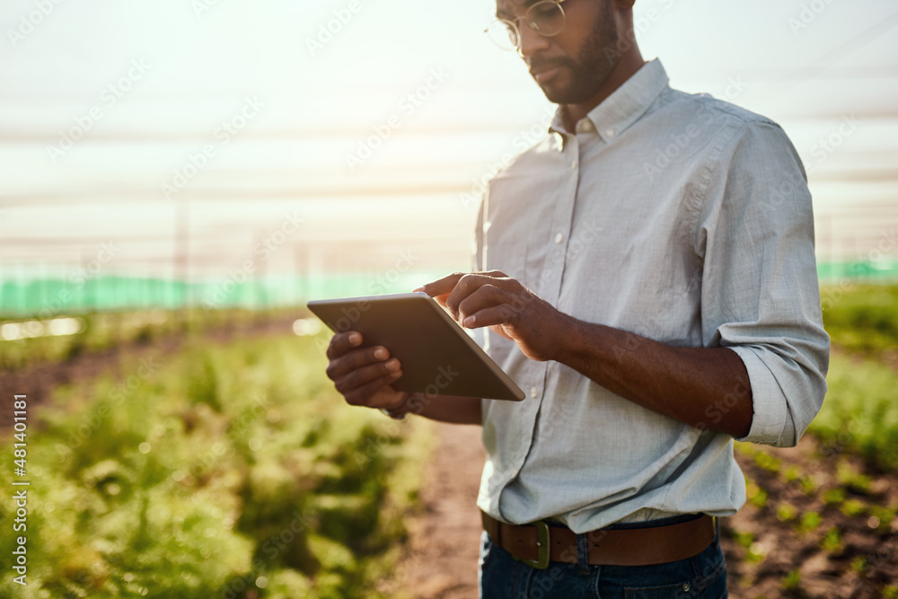 Its the future of farming. Cropped shot of a handsome young male farmer using a tablet while workin