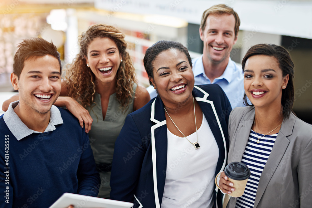 Coming together for the teams success. Portrait of a group of smiling coworkers standing in an offi