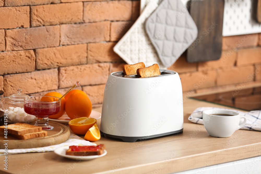 White toaster with tasty breakfast on counter near brick wall