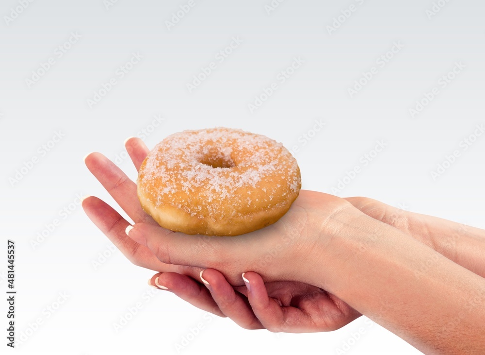 Hand holds Hanukkah donut with jam on the background.