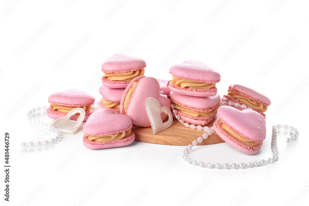 Tasty heart-shaped macaroons and beads on white background