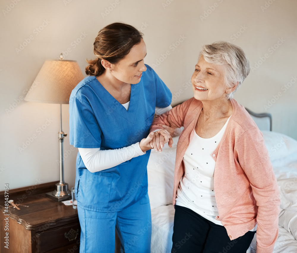 Im ready for a day out. Shot of a young nurse helping a senior woman get up from her bed in a nursi