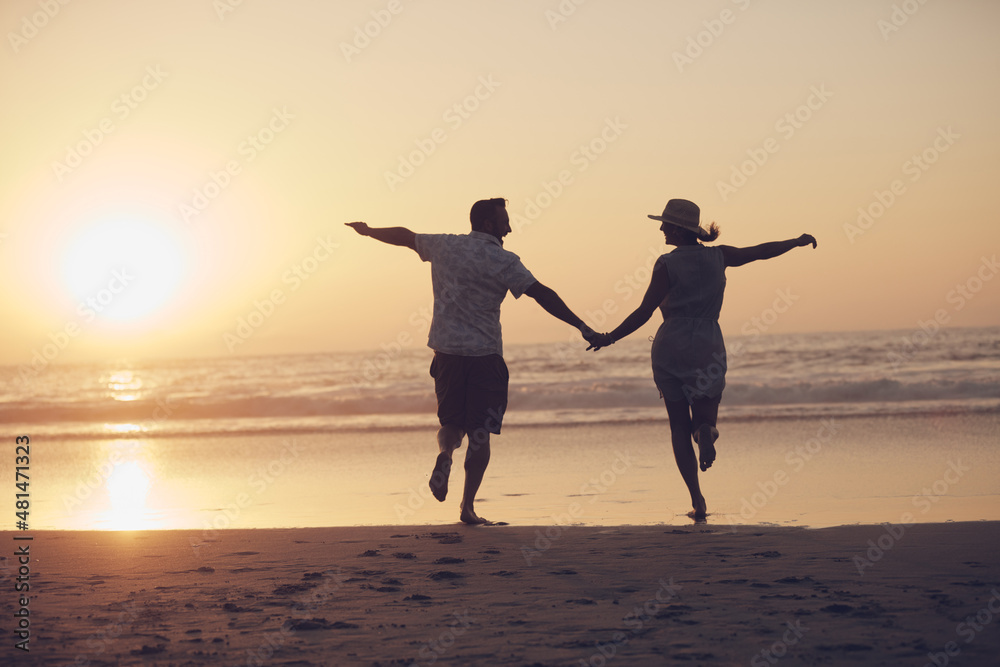 Off into the sunset they went. Shot of a mature couple running on the beach.