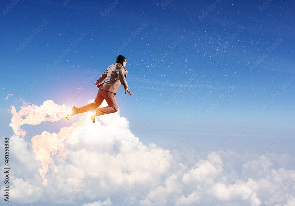 Businessman in suit and aviator hat flying in sky