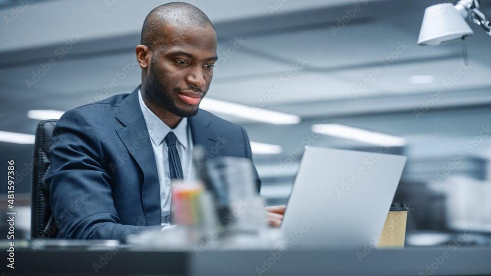 Office: Happy Successful Black Businessman Sitting at Desk Using Laptop Computer. African American E