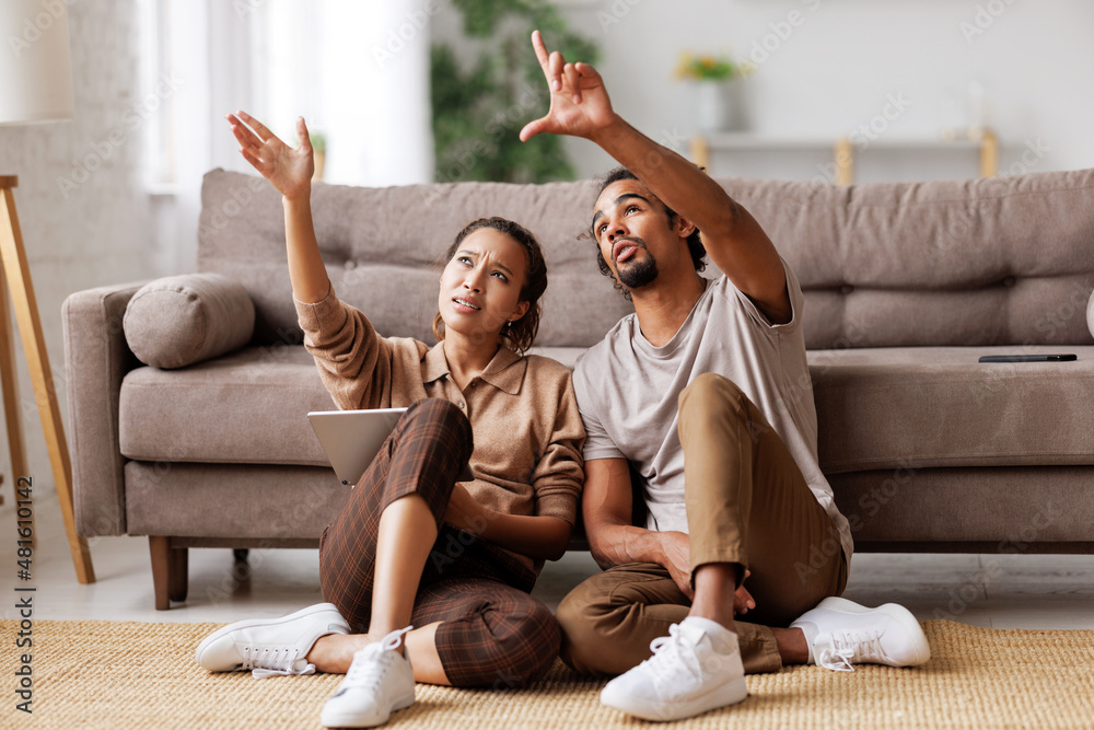 Young african american family couple planning home renovation, discussing design project on tablet