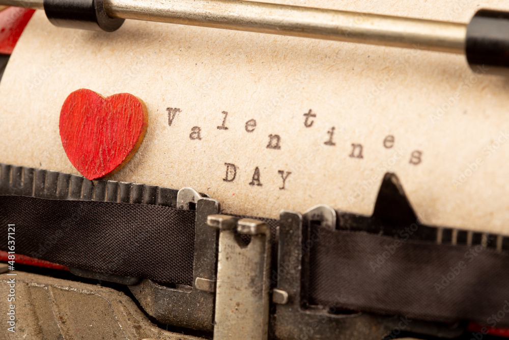 Happy Valentine`s day - phrase on typewriter. Valentines Day greetings concept. Little red wooden he