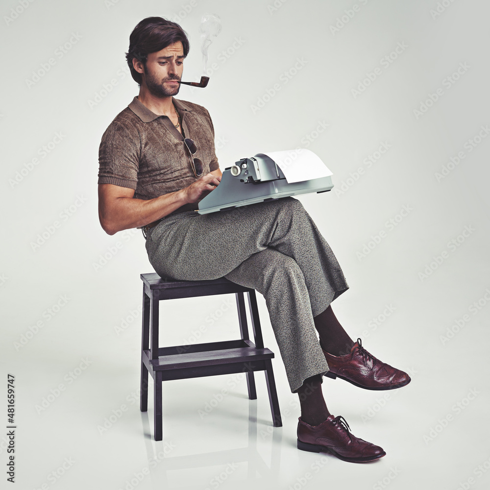 Who needs a desk anyway. Studio shot of a 70s style businessman sitting on a stool using a typewrit