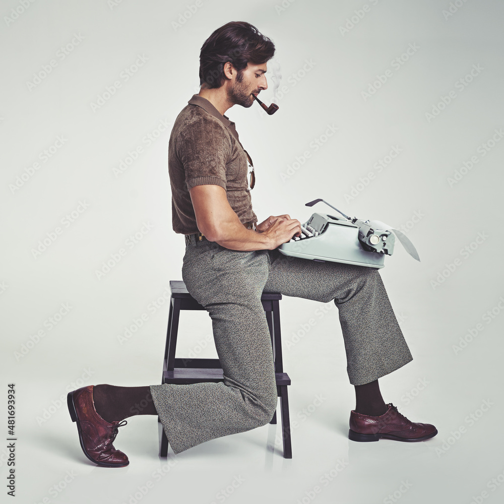 Who needs a desk anyway. Studio shot of a 70s style businessman sitting on a stool using a typewrit