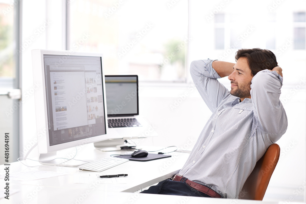 Loving the look of his progress. Shot of a handsome young businessman reclining in his chair while u