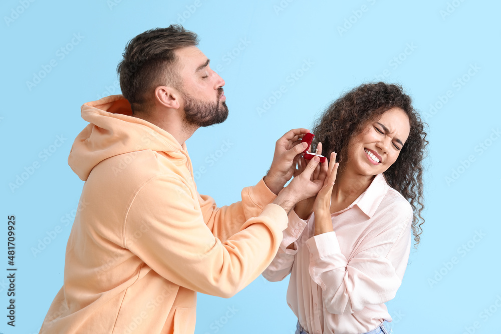 Young African-American woman rejecting marriage proposal on color background