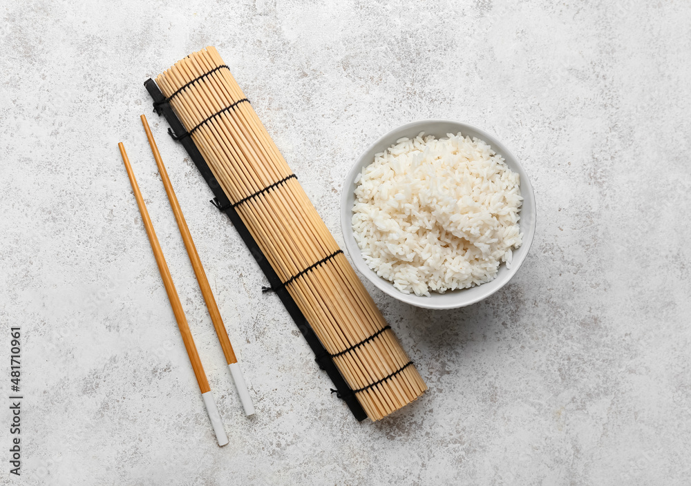 碗里有美味的煮米饭、筷子和垫子，背景为浅色