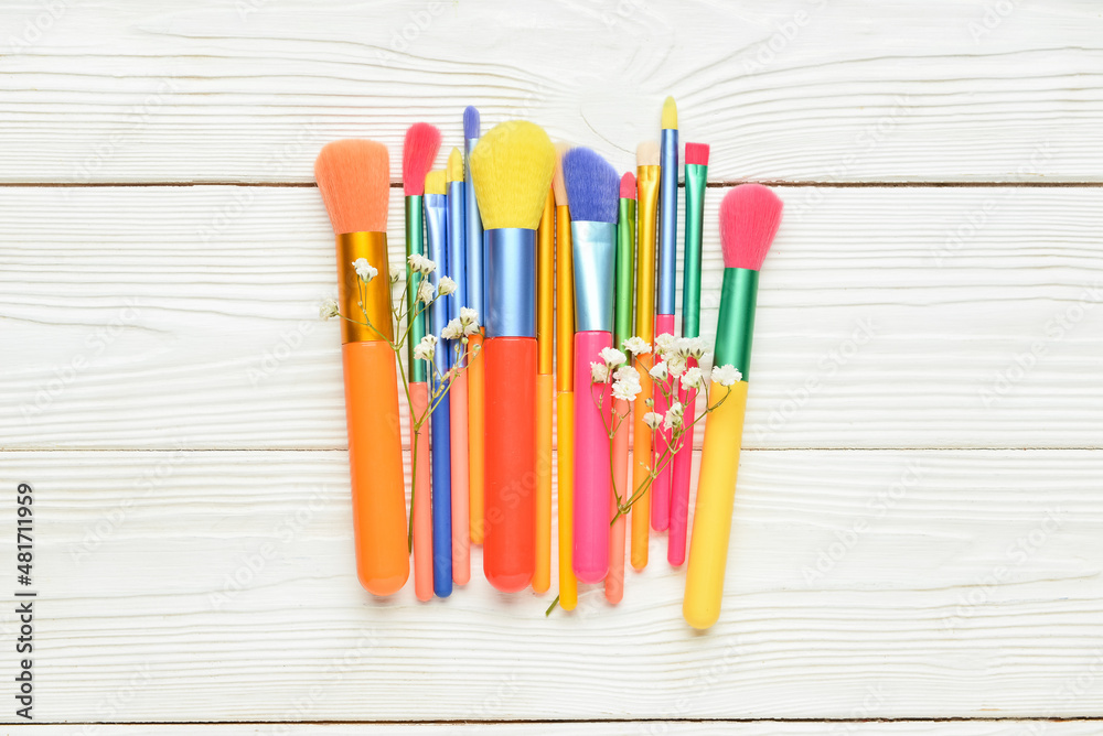 Set of makeup brushes on light wooden background