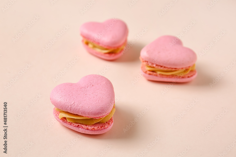 Tasty heart-shaped macaroons on beige background