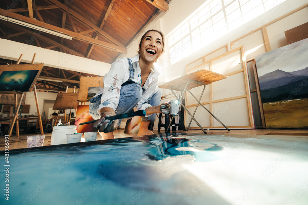 Painter laughing cheerfully while working in her art studio