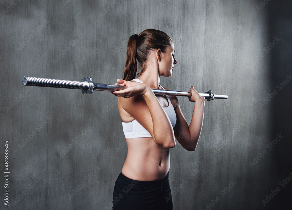 Shes getting stronger with each workout. Shot of a woman working out with a barbell at the gym.