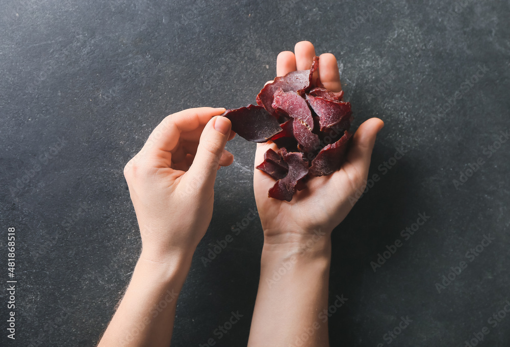 Female hands holding beef jerky on dark background