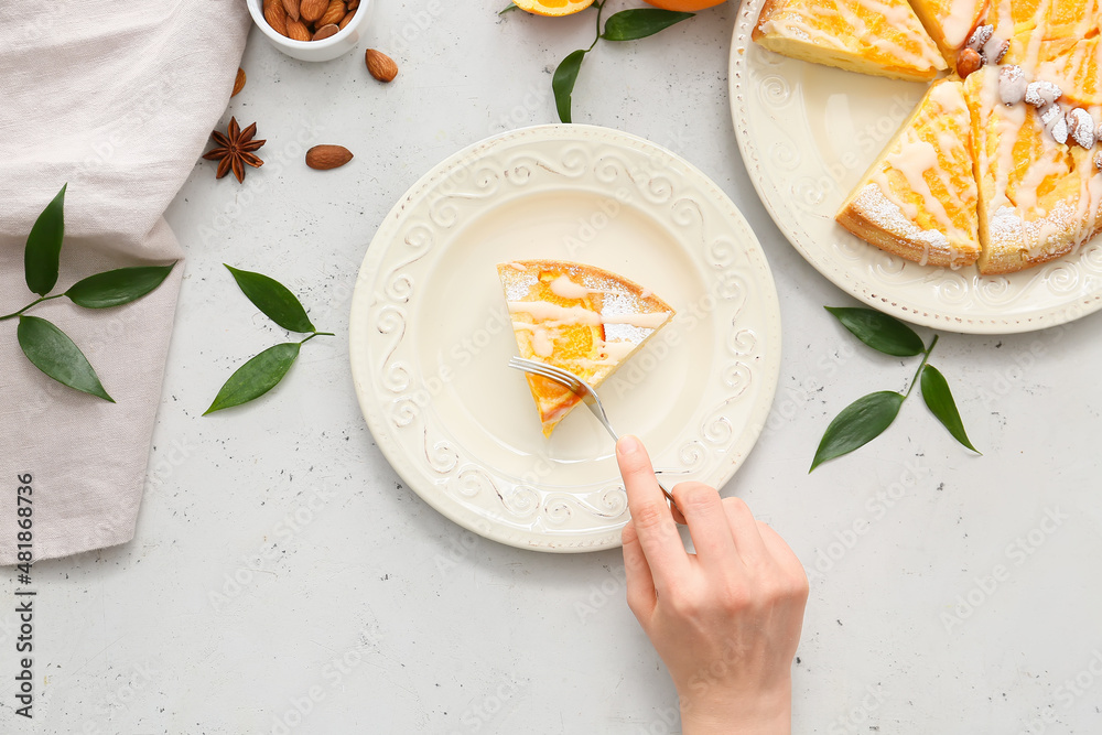 Woman eating tasty citrus cake with oranges from plate