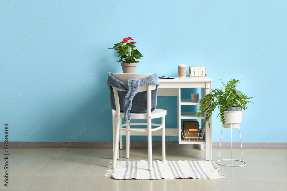 Workplace with Anthurium flower, calendar and paper cup of coffee in room