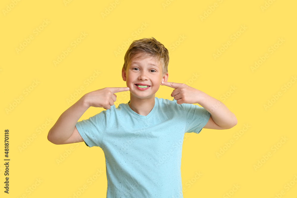 Little boy pointing at chewing gum on yellow background