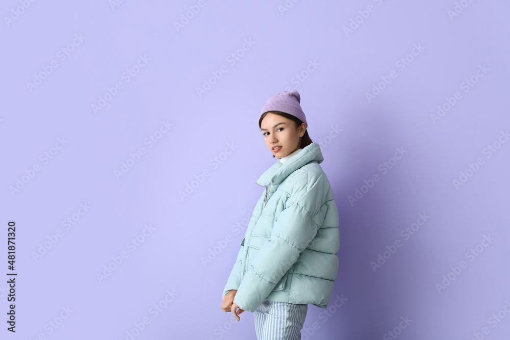 Pretty young woman in stylish warm clothes on color background