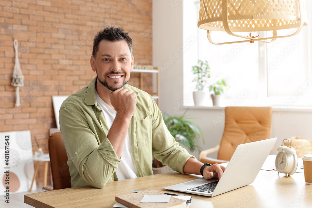 Handsome man working with laptop at table in office