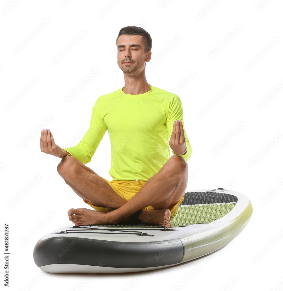 Young man meditating on sup board against white background