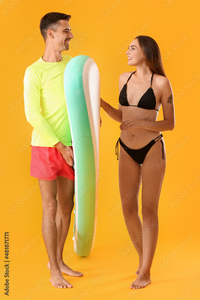 Young couple with board for sup surfing on color background