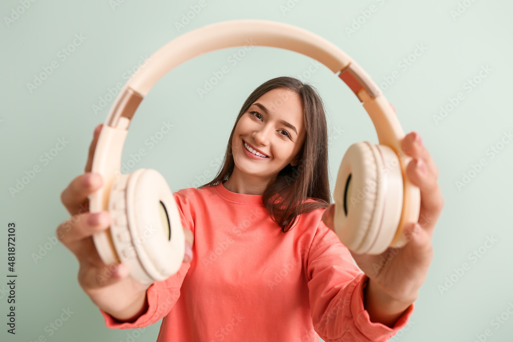 Cool young woman with headphones on color background