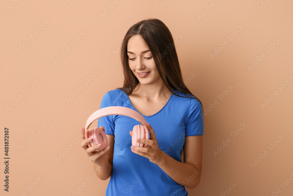 Cool young woman with headphones on color background