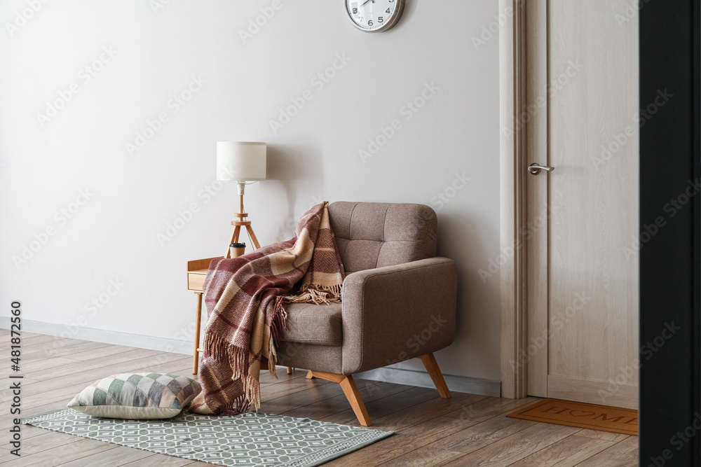 Interior of modern room with armchair and table near light wall