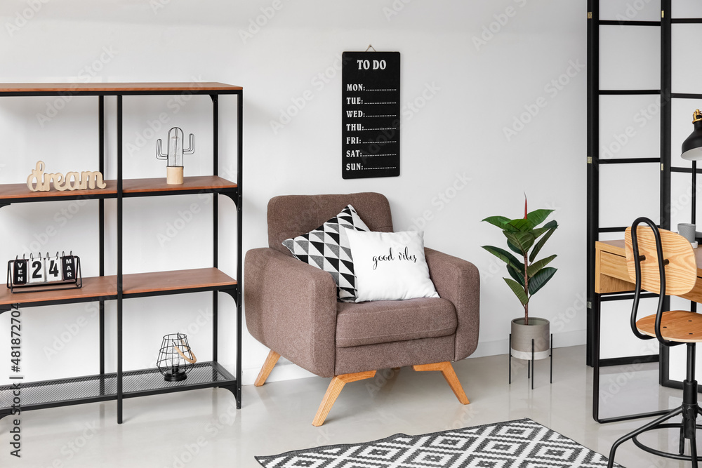 Interior of light living room with soft armchair and shelving unit