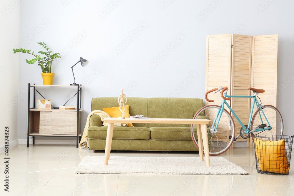 Interior of modern flat with sofa, folding screen, table and bicycle