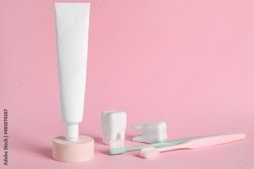 Tube with toothpaste and toothbrushes on color background