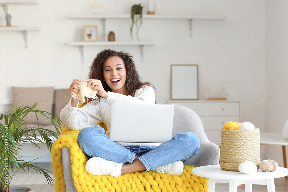 Young African-American woman taking online knitting classes at home