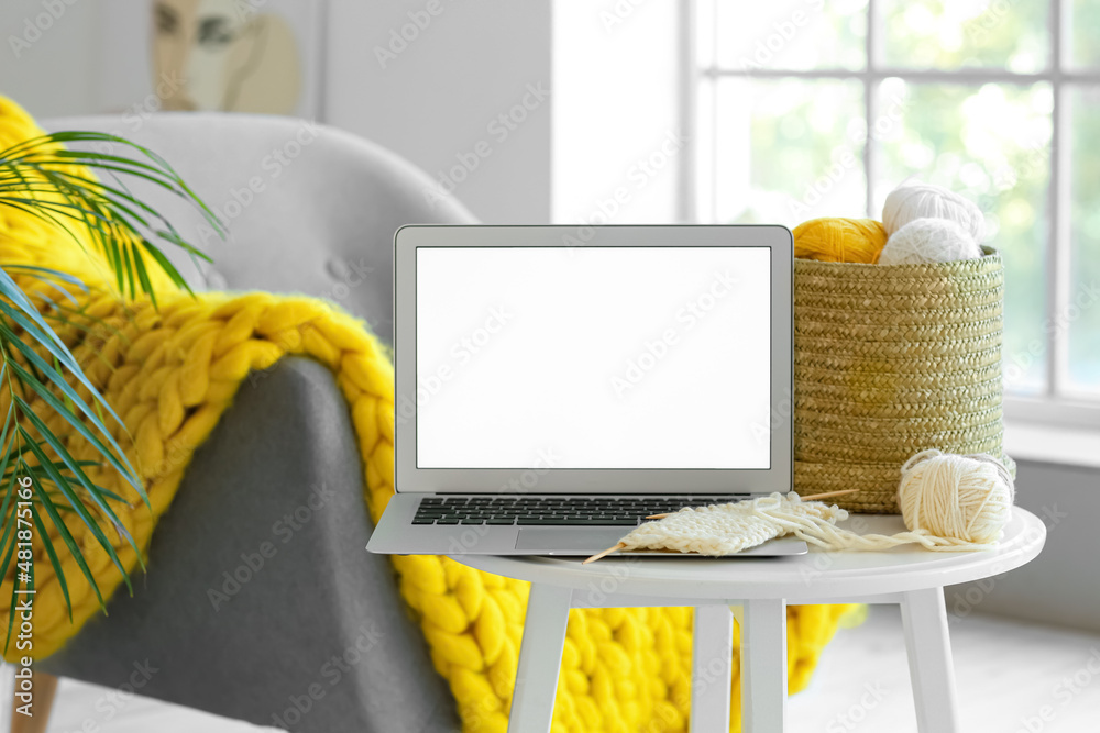 Laptop and knitting threads on table