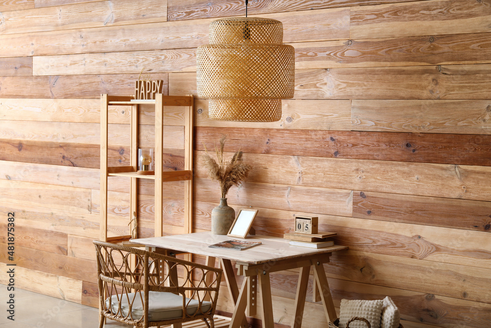 Interior of stylish room with modern workplace, shelving unit and hanging lamp