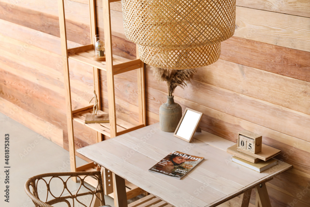 Interior of stylish room with modern workplace, shelving unit and hanging lamp