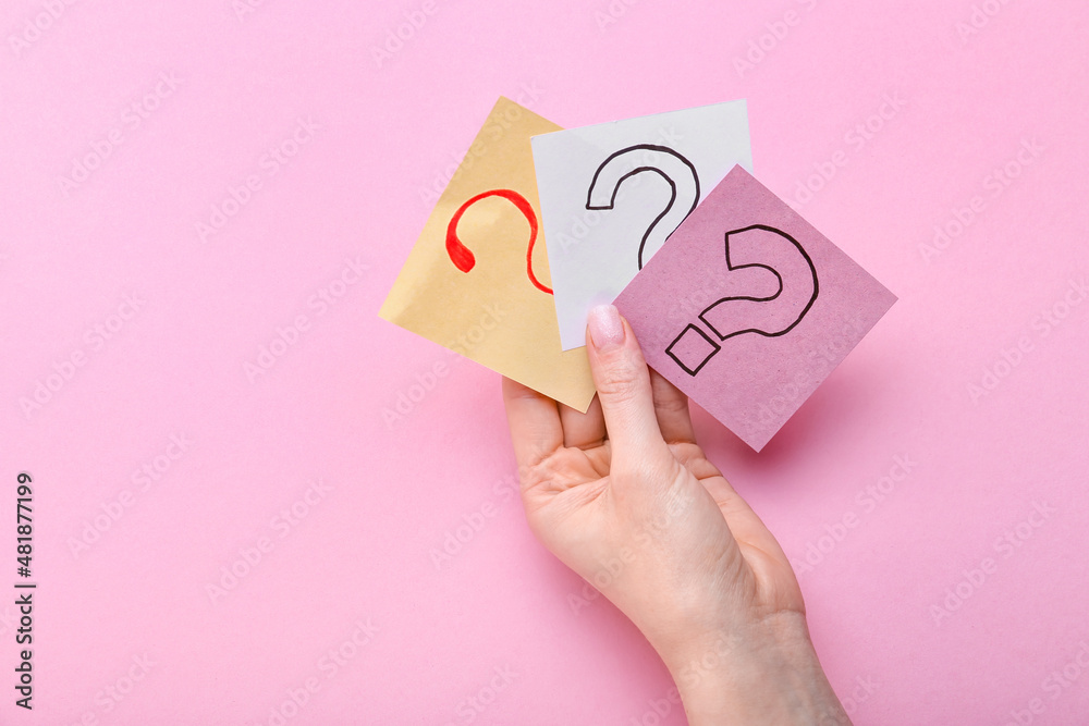 Woman holding sticky notes with question marks on pink background