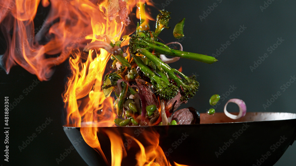 厨师将牛肉混合物从锅中倒入火中的特写镜头。